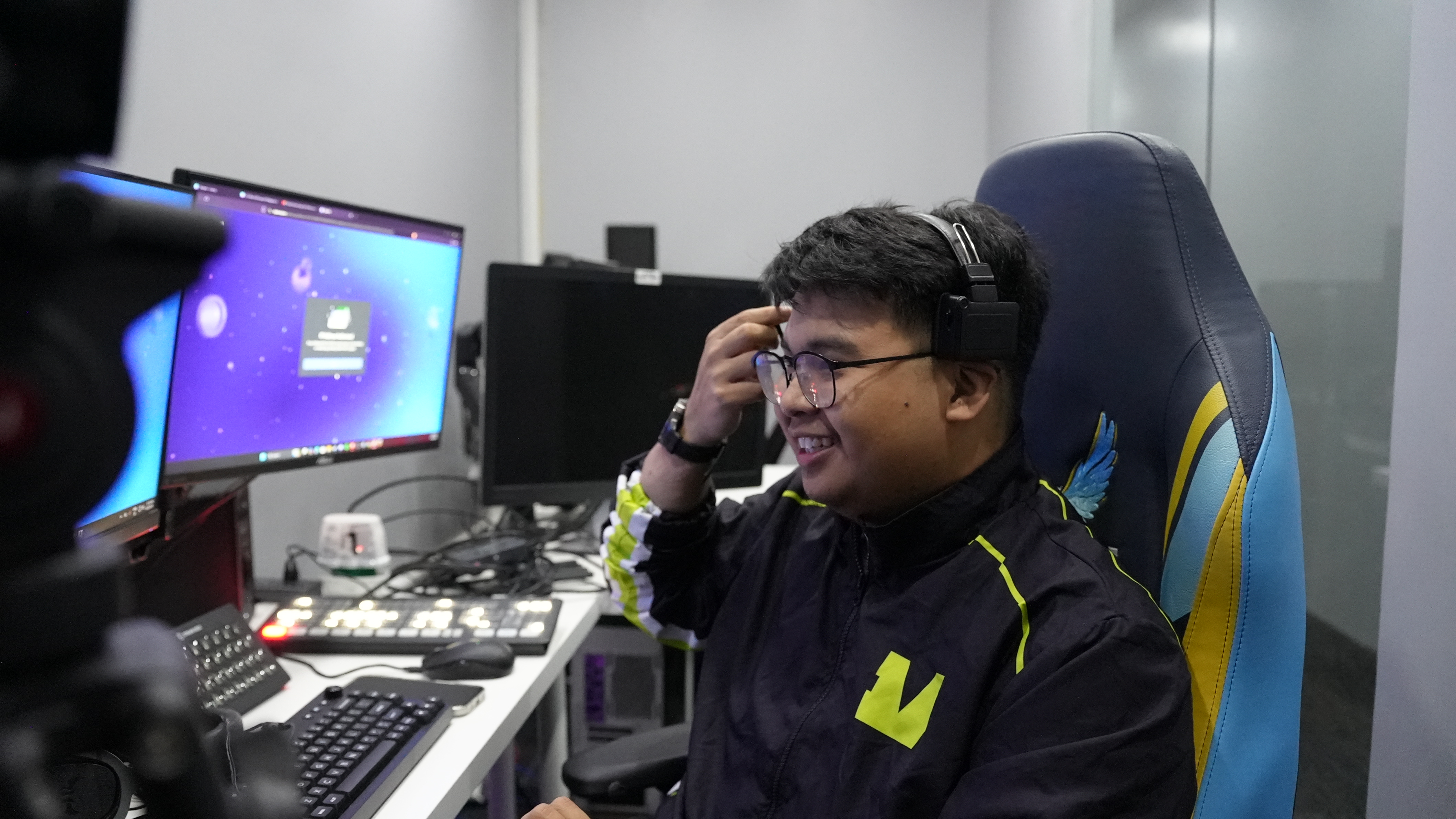 Person wearing a headset at a multi-monitor streaming and control desk