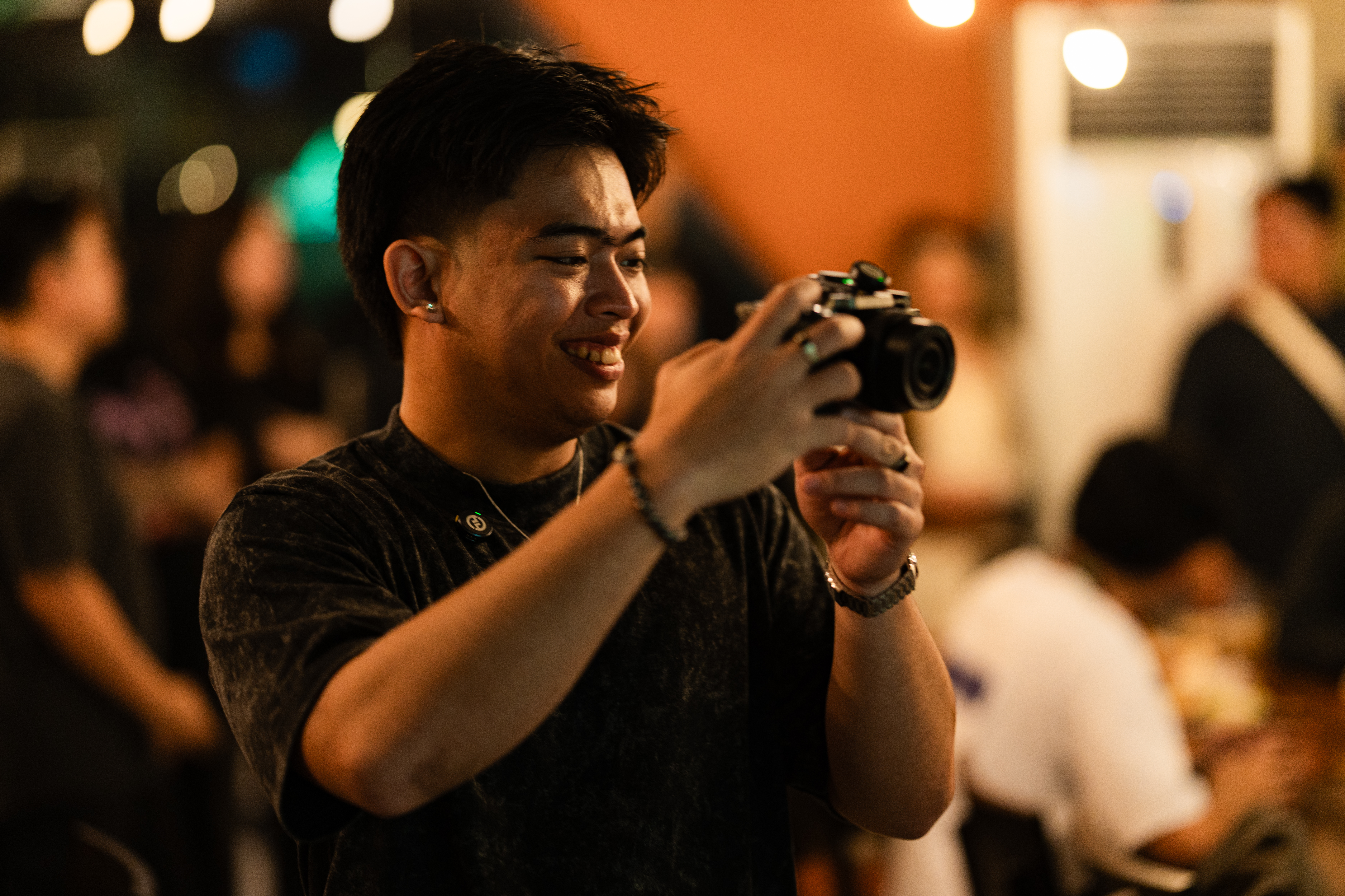 Photographer holding a mirrorless camera at an evening event