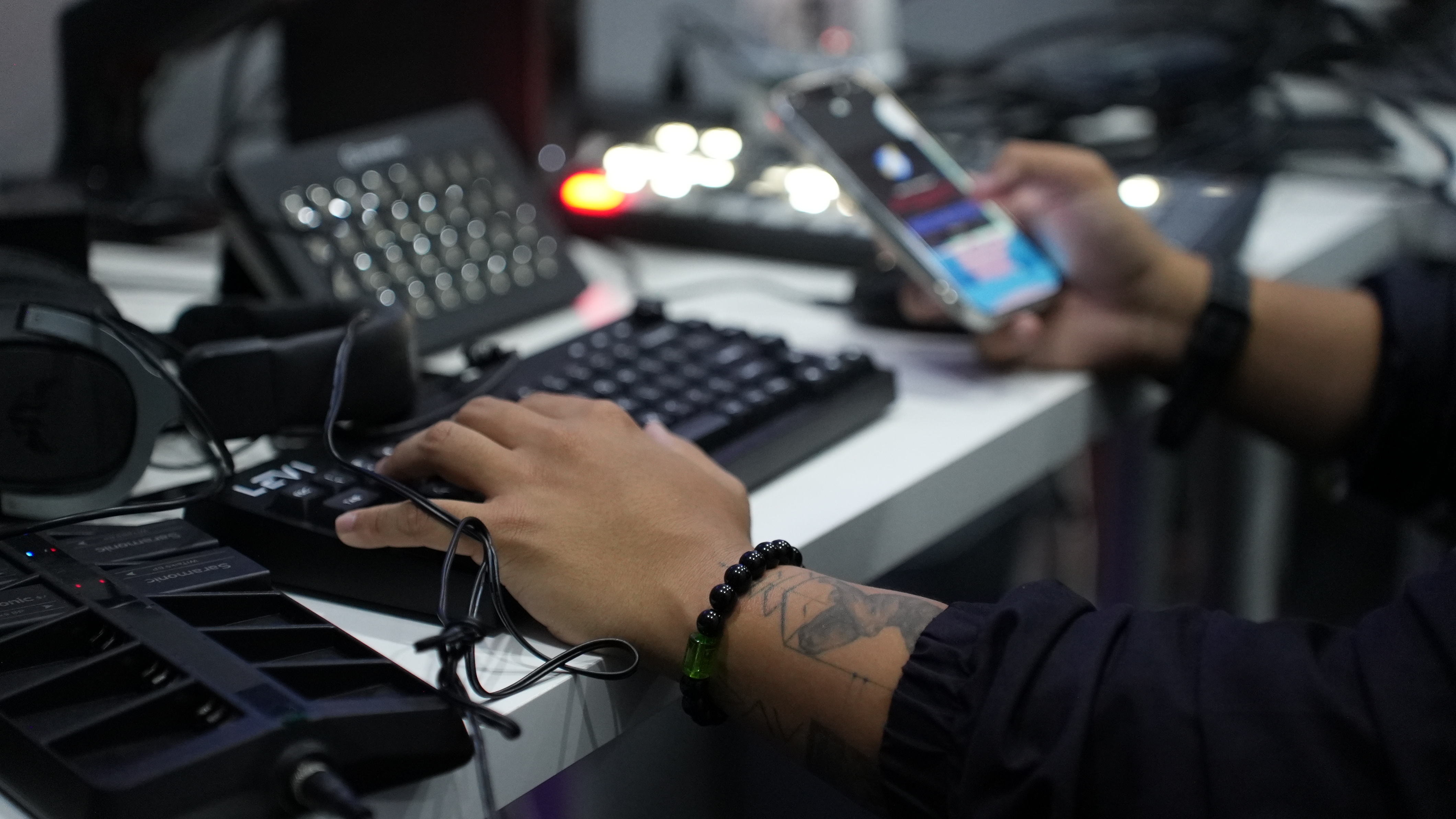 Close-up of hands operating a streaming control deck and a phone