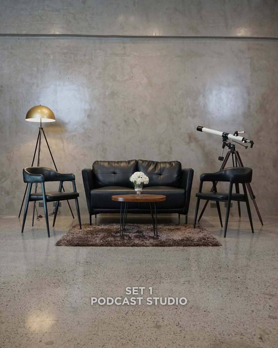 Styled studio set with lounge seating and signage reading "Set 1: Podcast Studio"