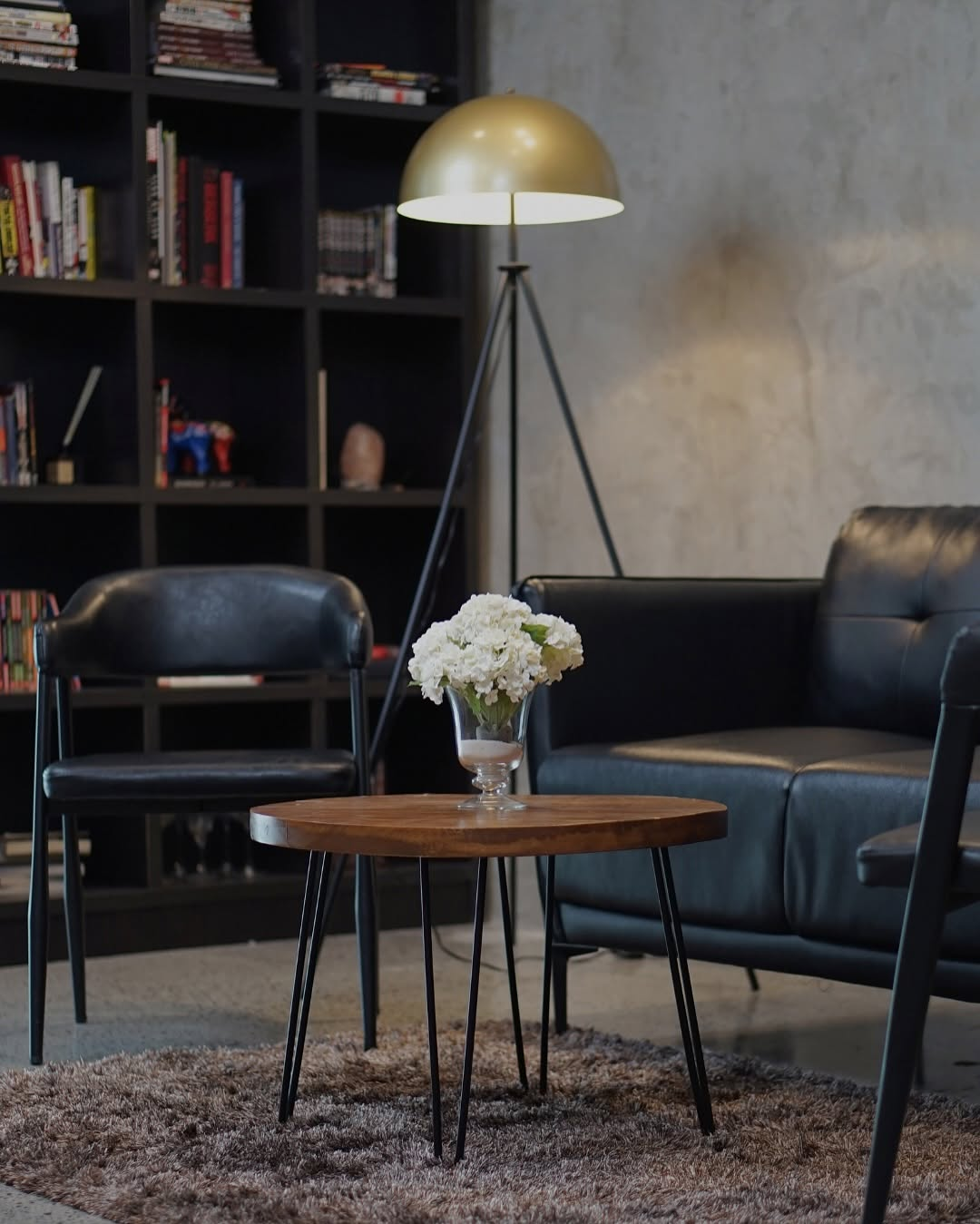 Furnished studio lounge corner with a bookshelf, lamp, and seating